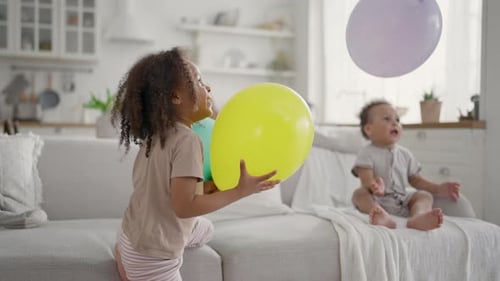 Children Play with Balloons on Sofa at Home