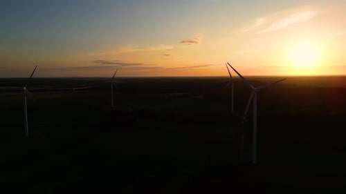 Silhouette of a windmill in the sun. Aerial close up shot of wind mills rotating by the force of the