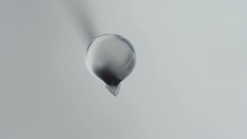 A medical syringe with a vaccine dripping from a needle. Reflection in a drop. Close-up.