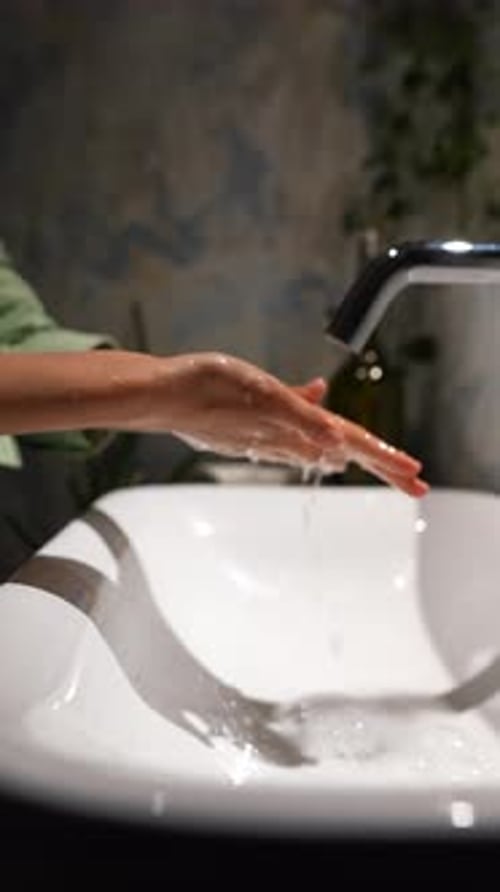 The View From Above Captures a Woman's Hands Positioned Under a Water Tap