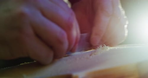Macro au ralenti d'un maître artisan luthier effectuant un travail minutieux et détaillé sur un violon en bois dans un atelier
