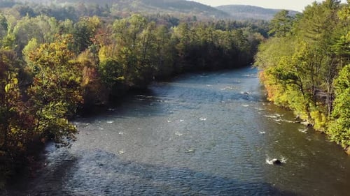 Drone tilt up shot of Housatonic river passing by with dense forest on both sides in the hilly terra