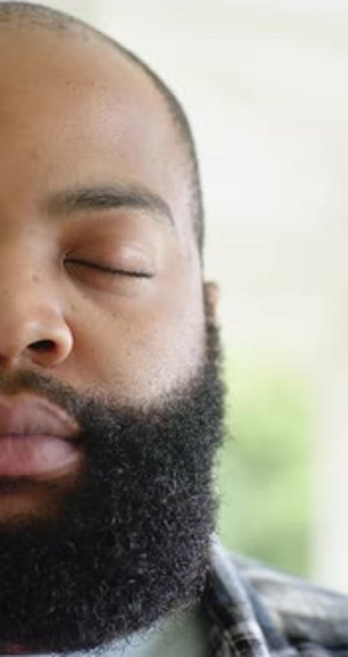 Homme afro-américain réagissant à la lumière vive du porche, clignotant, ouvrant les yeux, souriant en chemise à carreaux