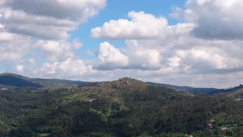 Malerische Landschaft mit sanften Hügeln und viel Grün unter einem lebendigen Himmel mit Wolken