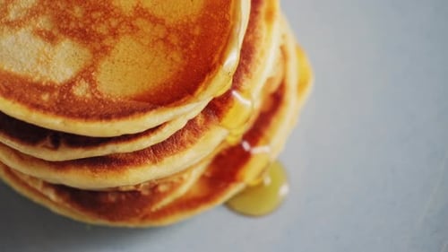 Close Up Pouring Honey Over Stack of Pancakes Concept of Sweet Brunch