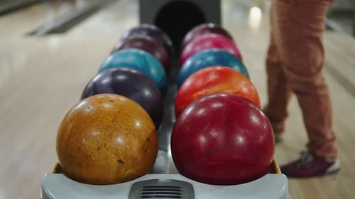 Teenager nimmt den rosa Ball vom Ballrückgabeständer an der Bowlingbahn