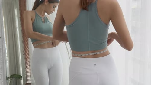 Woman Measures Waistline in Mirror at Home