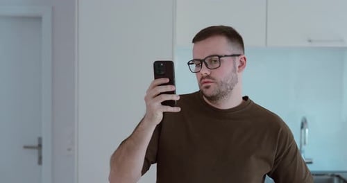 Young Man Using Smartphone in Kitchen – Close Up