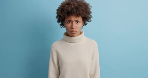 Young Woman Pouting Against Blue Background, Facial Expressions