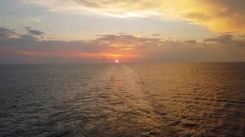 Ein pulsierender Sonnenuntergang über dem Meer mit einem Boot, das ruhig schwimmt