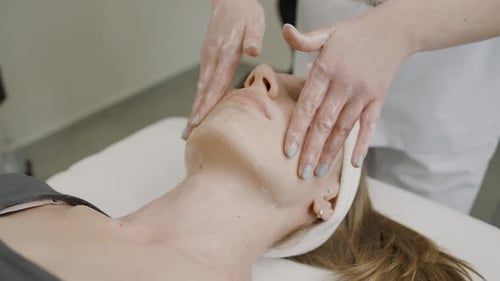 Woman receiving facial massage in spa salon