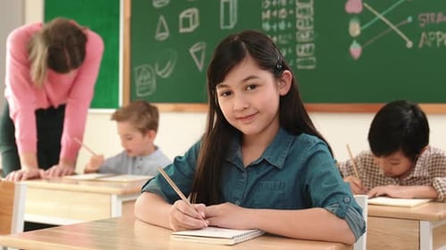 Young girl writing at her desk in a classroom