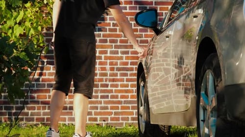Man Charging Electric Car on Sunny Day