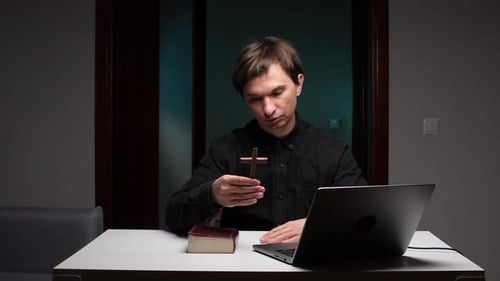 Priest Holding Cross and Leading Online Church Service with Laptop and Bible