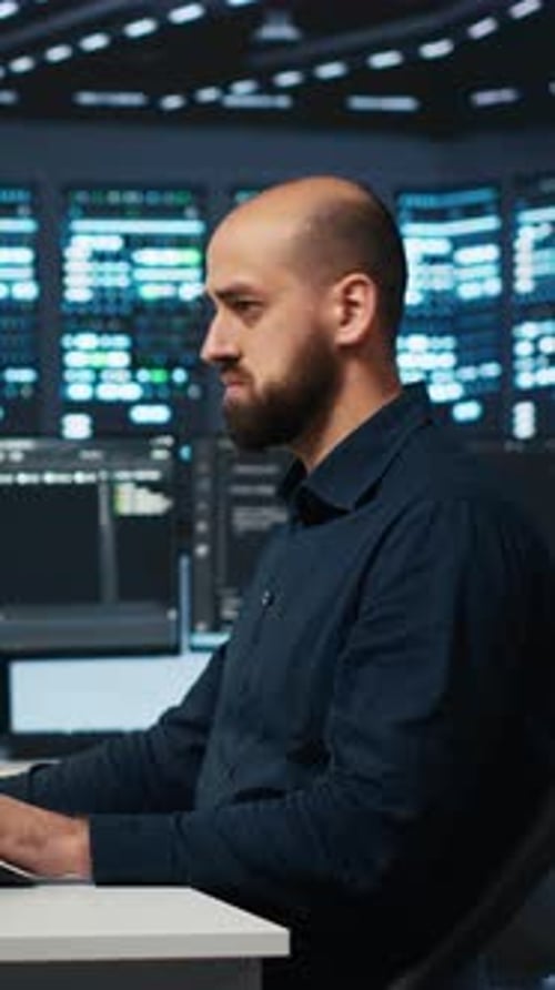Man Types at Computer in Dark, Futuristic Office