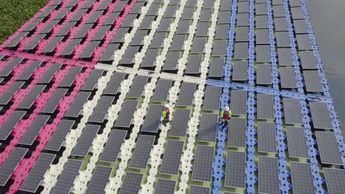 Ansicht von oben und zirkulieren zwei Techniker gehen spazieren und diskutieren über Solarzellenmodule über Wasser