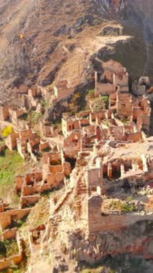 Drone Captures Panoramic View of Historic Hillside Settlement Amid Autumn Foliage and Rugged Terrain