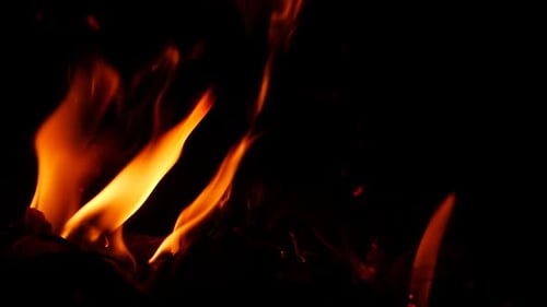 Zoomed in video of fire burning in darkness yellow flame