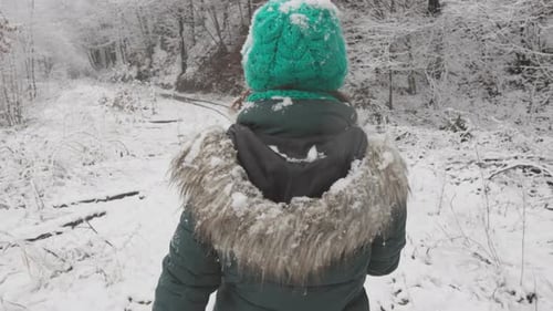 Wearing a Green Hat the Woman Leisurely Walks Through the Winter Wonderland Taking in the Peaceful