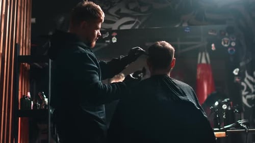 Barber Giving Haircut with Clippers in Dark Barbershop
