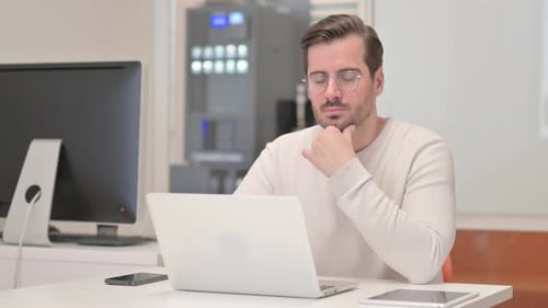 Thoughtful Man Working on Laptop in Office