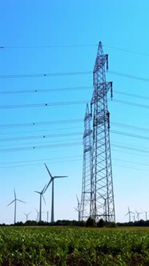 Wind turbines and power lines. Wind turbines rotate in the field