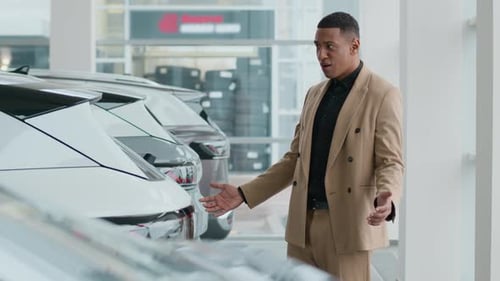 Man in Suit Looks at Cars in Showroom