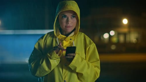 Woman in raincoat uses phone in the rain