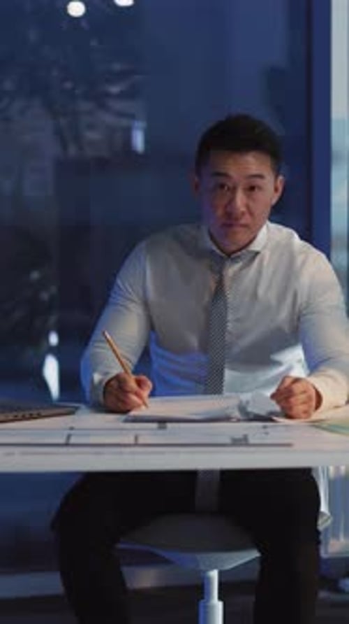 A Businessman Engaged in Writing Work Late Night in a Modern Office Environment Setting