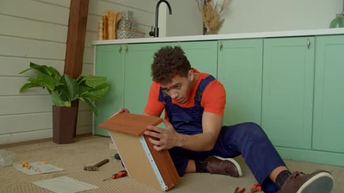 Un bricoleur noir positif termine l'assemblage d'un tiroir de table de chevet à faire soi-même