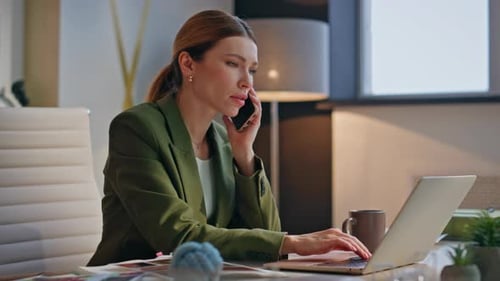 Serious Woman Talking on Cell at Office Desk
