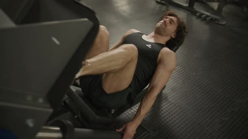 Athletic Man Performing Intense Leg Press Workout in Gym