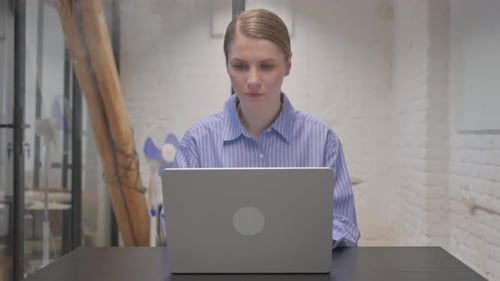 Woman with Headache Rubbing Temples at Desk