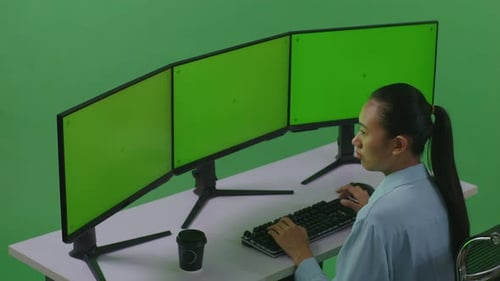 Side View Of Asian Woman Working With Mock Up Multiple Computer Monitor In Green Screen