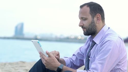 Joven empresario disfrutando de un trabajo digital junto a la playa en unas soleadas vacaciones de verano