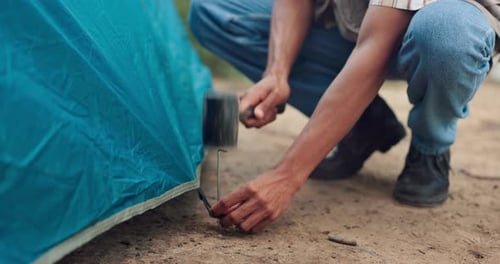 Hands, hammer and tent to prepare for camping with building, survival or vacation in nature