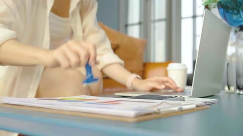 Close-up Of Business woman is hand stamping with approved stamp on document on the table and laptop