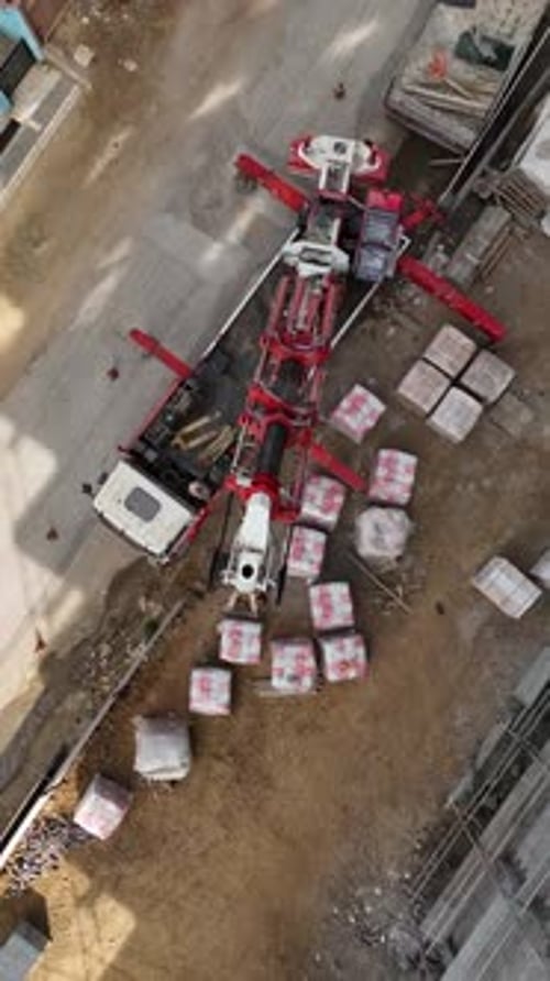 Vertical Video Construction Site Action Crane Unloading Cargo Builders at Work