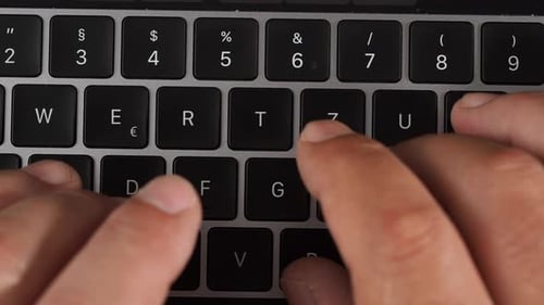 Ein Mann tippt auf einer Laptoptastatur.