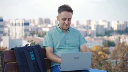 Man Working on Laptop in City Park