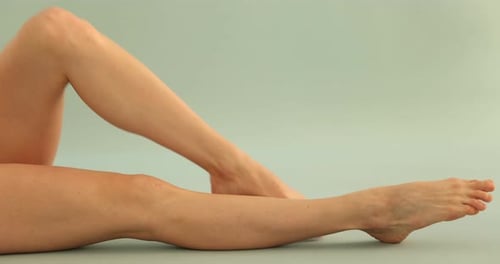 Woman showing legs with smooth skin on light background, closeup