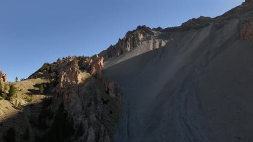 Drone volant en arrière avec la caméra inclinée vers le bas, filmant des montagnes et des sommets