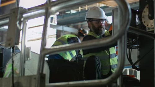 Two Heavy Industry Technicians Work with Equipment at Manufacturing Factory