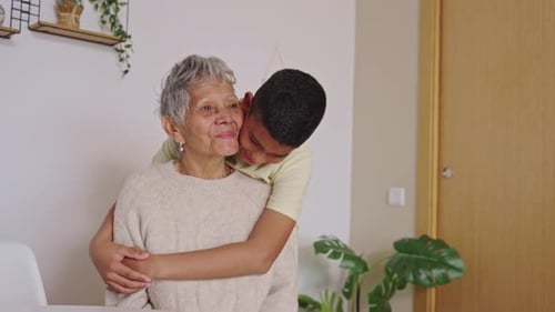 Grandson Hugs Loving Grandmother in Home Interior