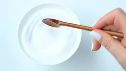 Erythrol sweetener in glass bowl on white background, top view.