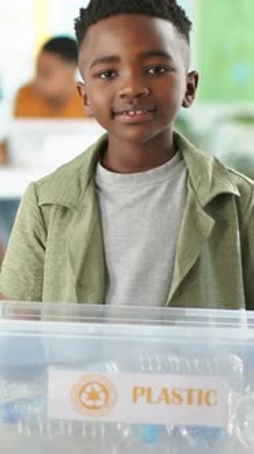 Vertical video: Recording pupil in green shirt presenting recycling bin in class showing bottles