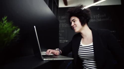 Young businesswoman works on laptop dreaming of success in bright modern office