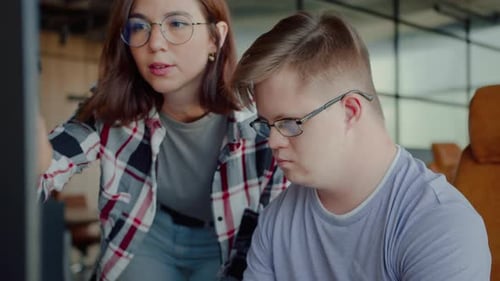 Woman Helping Young Man With Computer at Office