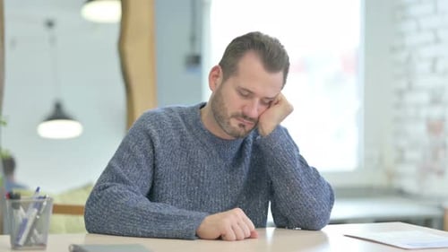 Hombre de mediana edad durmiendo sentado en el trabajo