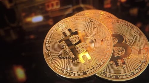 Close-Up of Golden Bitcoin Coins Reflecting Orange Lights